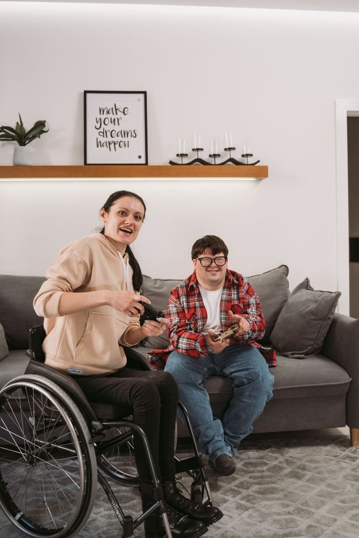 Young adults with disabilities enjoying leisure time together indoors, sitting and smiling.